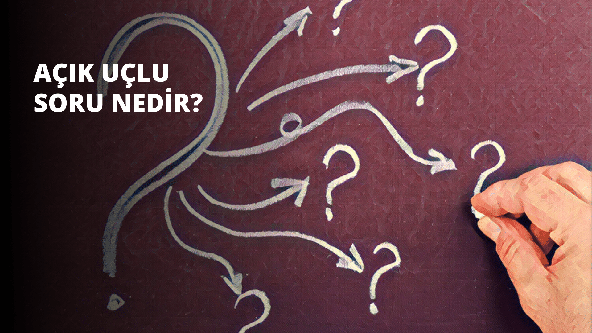 Canlı kırmızı bir yüzey üzerine beyaz tebeşirle çizim yapan bir elin yakından görünümü. Çizim bir dizi ok ve soru işareti içeriyor. Okların ucu sivri ve merkezden spiral bir şekilde uzanıyor. Soru işaretleri hafif kavisli bir şekle sahip olup ortadaki halka dışarıdaki iki halkadan daha büyüktür. Oklar ve soru işaretleri dikkatli ve hassas bir şekilde çizilmiştir, bu da onları yapan kişinin çalışmalarına büyük bir düşünce kattığını göstermektedir. Çizimin arkasındaki arka plan, çeşitli tonlar ve şekiller içeren parlak ve renkli bir tuvaldir.