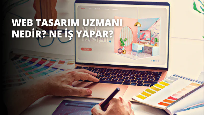 Resimde dizüstü bilgisayar kullanan bir kişi görülüyor. Dizüstü bilgisayar siyah bir masa üzerinde açık ve kişi dizüstü bilgisayarın ekranına bakıyor. Elleri dizüstü bilgisayarın klavyesinin üzerine yerleştirilmiş. Arka planda, kalem tutan bir elin bulanık bir yakın çekimi ve bir klavyenin yakın çekimi görülüyor. Kişinin sağında bir bilgisayar ekranı ve bir telefon görülüyor. Kişi beyaz bir gömlek ve mavi bir kot pantolon giymektedir. Görüntü geniş bir açıyla çerçevelenmiş ve renkler canlı ve parlak.