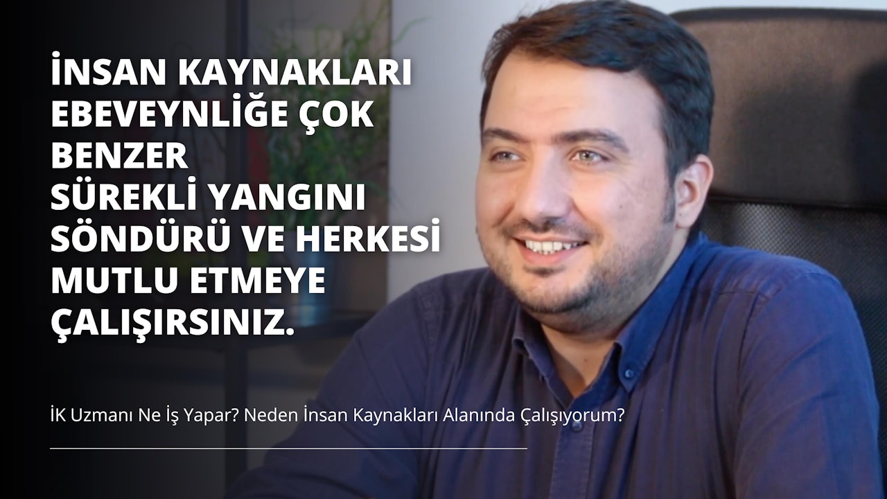 Sakallı bir adam kameraya gülümsüyor. Lacivert düğmeli bir gömlek giymiş ve arka planda yeşil bir bitki olan bir sandalyede oturuyor. Fotoğrafın sağ tarafında gri zemin üzerine beyaz bir harf ve siyah zemin üzerine üç beyaz harf var. Adam dostça bir ifadeyle doğrudan kameraya bakıyor. Yüzündeki saçlar düzgünce kesilmiş ve bir gözlük takıyor. Arka plandaki ışık yüzünü vurguluyor ve çerçevedeki renkleri aydınlatıyor. Fotoğraf bir neşe ve mutluluk anını yakalıyor.