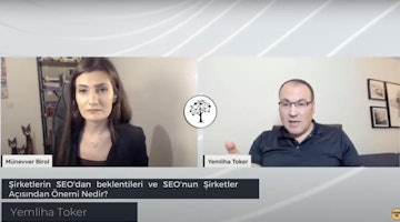 Bir adam ve bir kadın hararetli bir konuşma yapıyor. Kadının uzun, siyah saçları vardır ve siyah bir ceket giymektedir. Adam ise gözlük ve açık mavi bir gömlek giymektedir. Arka planda nokta ve çizgilerden oluşan siyah beyaz bir ağaç ve duvarda bulanık bir resim çerçevesi var. Arkalarında bir video konferansın ekran görüntüsü var. Ön planda beyaz bir yüzeyin yakın çekimi ve açık mavi metinli bir tabelanın yakın çekimi var. Gözlüklü adam doğrudan kadına bakıyor ve kadının söylediklerini dikkatle dinlediği izlenimini veriyor. Ortam aydınlık ve davetkârdır.