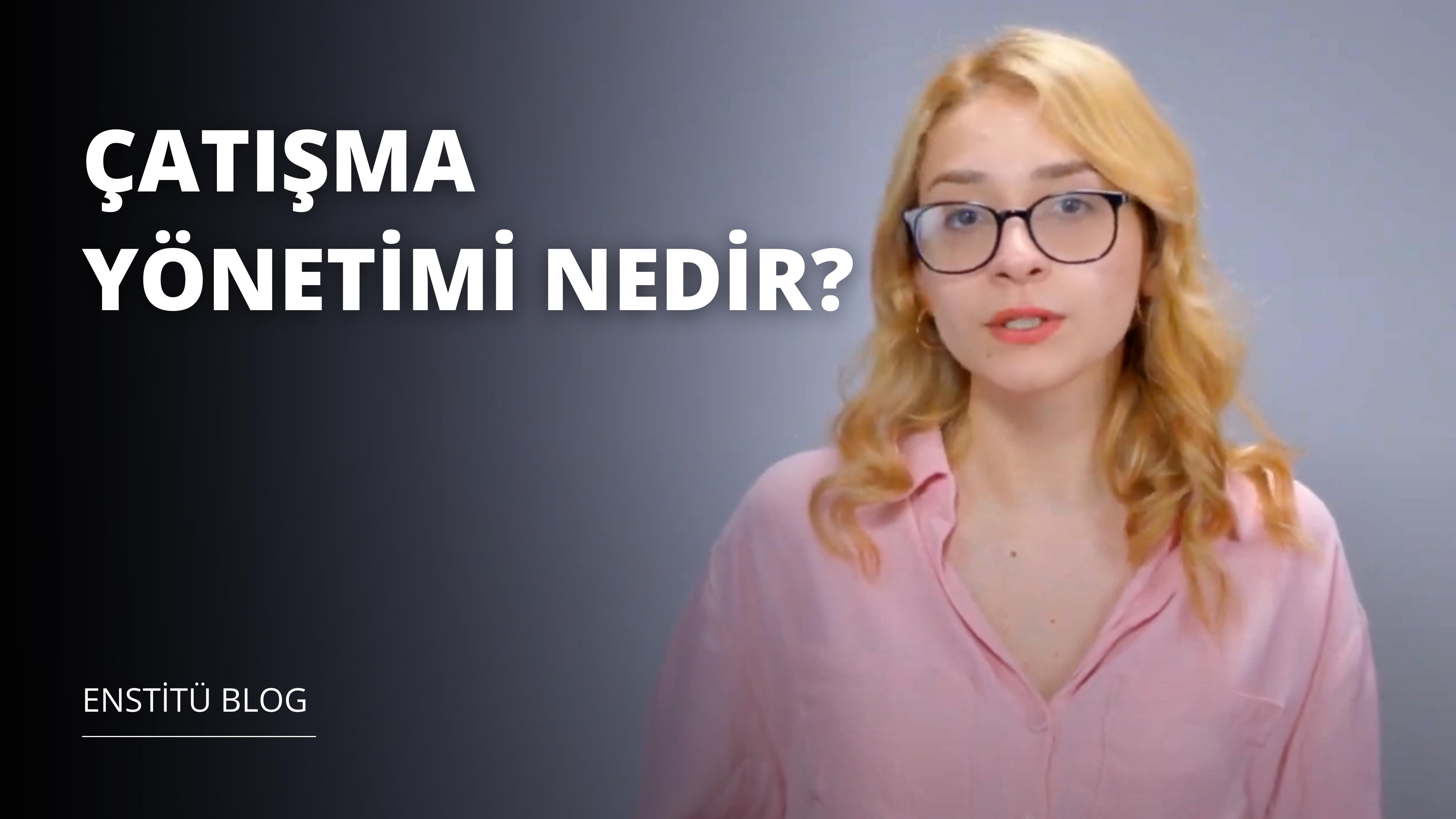 Resimde sarı saçlı, gözlüklü bir kadın görülüyor. Gözleri büyük yuvarlak gözlüklerin arkasında dümdüz karşıya bakmaktadır. Pembe bir gömlek giymiştir ve yüzü yakın plandadır. Ağzı hafifçe açık ve göğsü de yakın plandadır. Arka planda siyah zemin üzerine beyaz harflerle siyah beyaz bir logo görülüyor. Görüntünün çözünürlüğü 3840x2160 pikseldir. Görüntüdeki kadının kendine güvenen bir havası var ve karşısına ne çıkarsa çıksın hazır görünüyor.