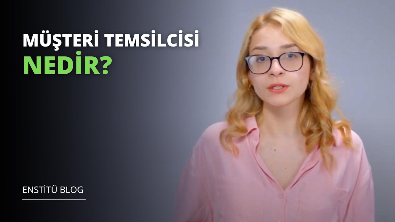 Sarı saçlı ve gözlüklü bir kadın gülümsüyor, parlak pembe bir gömlek giymiş. Gözlüklerinin üst kısmı hafif kavisli ve yüzünde dostane bir ifadeyle kameraya bakıyor. Dudakları hafifçe ayrılmış ve beyaz dişleri ortaya çıkmış. Arka plan siyah ve üzerinde beyaz bir harf var. Ayrıca yeşil ve beyaz bir metnin yanı sıra yeşil ve siyah bir logo da var. Yüzünün yakın çekimi mavi gözlerini ve açık tenini ortaya çıkarıyor. Göğsünün yakın çekimi kolyesini ve köprücük kemiğini gösteriyor. Genel olarak rahat ve mutlu görünüyor.