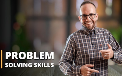 Featured in this image is an instructor, set against the blurred backdrop of a pleasing room with two large windows. Dressed in a brown and white checkered shirt, the instructor is visibly illustrating a problem-solving strategy. This image signifies a training session, tailored for individuals seeking to strengthen their problem-solving skills. It's evident that the online course encompasses vital elements like problem-solving and decision-making, critical thinking, and enhances the learner's overall problem-solving ability. This picture unmistakably showcases an educational setting where these significant skills are imparted to students.