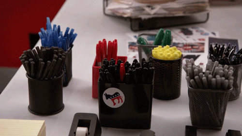 This is an image of a group of pens held neatly together in a black holder. The pens have a variety of bright colors which stand out against the dark background. The pens are securely held in place by a black plastic holder that has a curved design. The pens appear to be in an organized manner, with the pens of different colors stacked in alternating layers. The pens appear to be arranged in a neat, orderly fashion, which creates an aesthetically pleasing composition. The pens seem to be made of plastic, and the holder is made of a hard, durable material. The colors of the pens add a vibrancy to the image, which creates an attractive aesthetic.