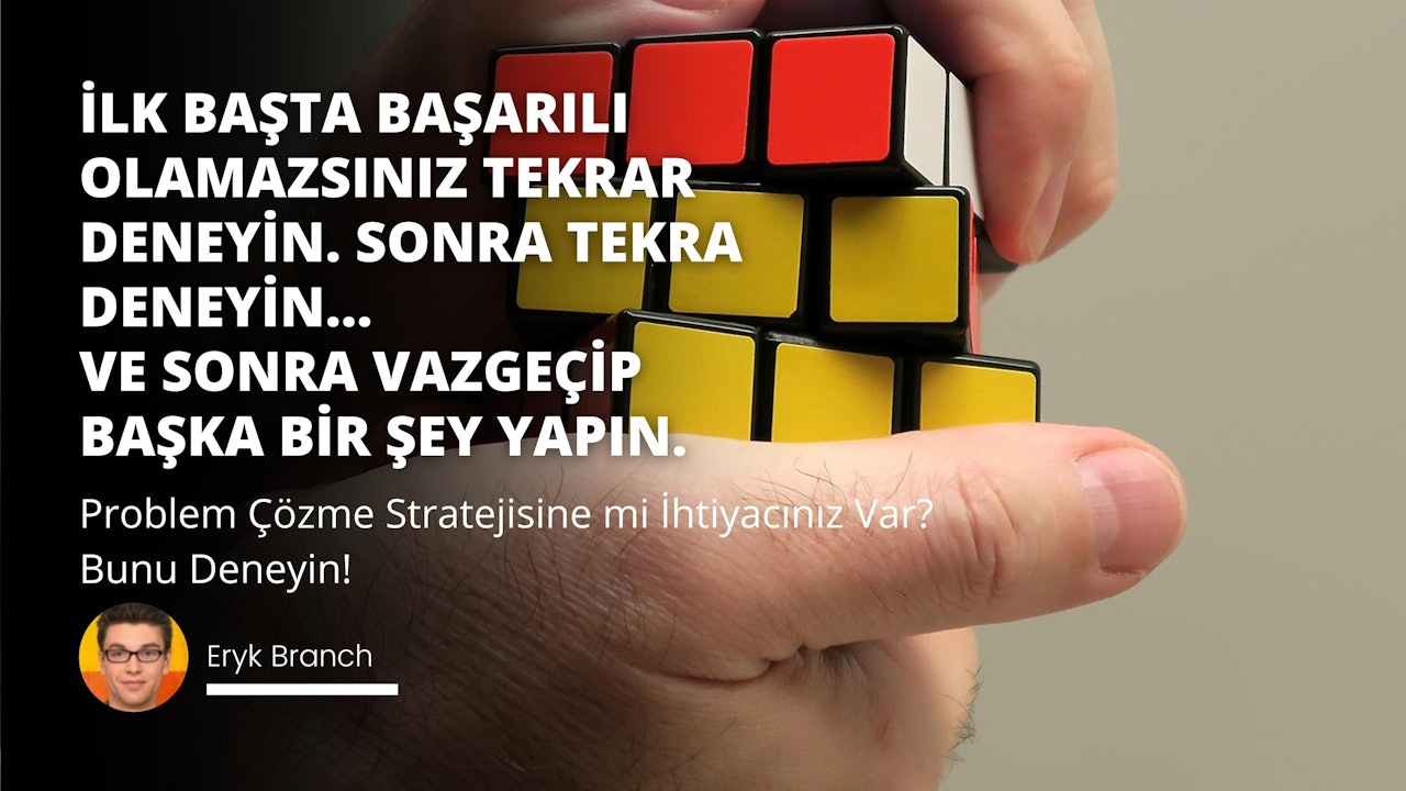 Renkli bir Rubik Küpünü kavrayan bir elin yakın çekimi. Elin parmakları küpün etrafına sarılmış ve başparmak dikkatlice üst yüzü tutuyor. Küp kırmızı, sarı, beyaz ve siyah gibi parlak renklerden oluşuyor. Arka plan siyahtır ve küpün ortasında siyah zemin üzerinde beyaz bir O harfi vardır. Küpün sağında kırmızı bir kare ve onun sağında siyah kenarlıklı sarı bir kare vardır. Sol üstte sarı ve siyah bir işaret var. Bu resim, bulmaca tutan bir el için harika bir örnektir.