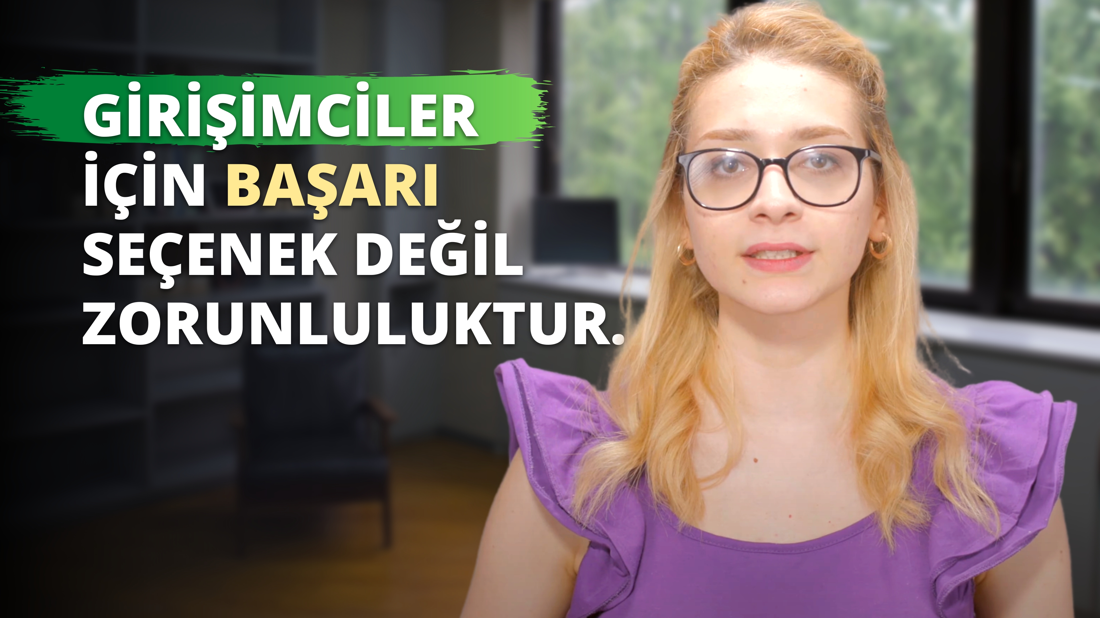 Gözlüklü ve mor gömlekli bir kadın yeşil ve beyaz bir logonun önünde duruyor. Kadın sarı saçlıdır ve logo arka planda açıkça görülmektedir. Kadının gözlerine yakından bakıldığında altın bir küpe görülüyor ve dudakları hafifçe ayrılmış. Resmin sağ tarafında siyah zemin üzerinde beyaz bir 'D' harfi ve sarı bir harf görülüyor. Kadın yüzünde kendinden emin bir ifadeyle dosdoğru karşıya bakıyor. Gözlükleri hafifçe renklendirilmiş ve mor gömleğinde karmaşık detaylar var. Arka plan bulanık ve ışık iyi dengelenmiş.