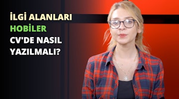 Görüntüde kırmızı flanel gömlek giyen ve gözlük takan bir kadın yer alıyor. Yüzünde ciddi bir ifade var ve doğrudan kameraya bakıyor. Bir kolye takıyor ve saçlarını topuz yapmış. Arka planda yeşil ve siyah bir işaret, siyah zemin üzerinde beyaz bir harf ve bulanık bir saat görüntüsü var. Resmin renkleri ağırlıklı olarak kırmızı, siyah ve beyazdır. Kadın görüntünün ana odağıdır ve merkezde ve biraz sağda yer almaktadır.