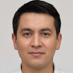 Güçlü bir çene çizgisine ve koyu renk, kısa saç kesimine sahip bir adam düz beyaz bir arka plan üzerinde duruyor. Gıcır gıcır beyaz yakalı bir gömlek ve siyah bir pantolon giyiyor. Yüz ifadesi sakin ve düşünceli, elleri iki yanında duruyor. Ayaklarını hafifçe açarak duruyor, gömleğini pantolonunun içine sokmuş. Gözleri koyu kahverengi ve sakince kameraya bakıyor. Duruşu kendinden emin ve rahat. Çenesinde hafif bir kirli sakal var ve kulakları saçlarının altından hafifçe görünüyor. Yirmili yaşlarının sonunda ya da otuzlu yaşlarının başında görünüyor.