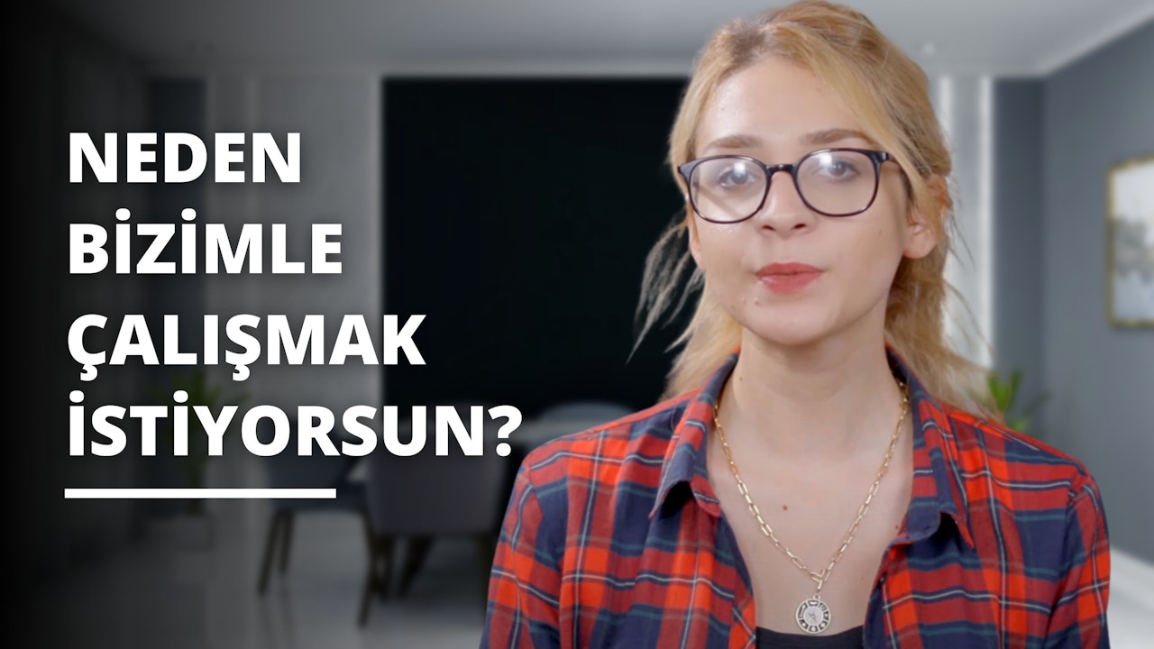 Gözlüklü bir kadın kırmızı beyaz flanel bir gömlek giyiyor. Boynunda kolye ucu olan bir kolye asılıdır. Yüzü yakın plandadır ve gözleri ileriye odaklanmıştır. Kulaklarının arkasına sıkıştırılmış açık kahverengi saçları var. Ayrıca yanaklarında hafif bir allık var. Arka plan bulanık ve beyaz bir nesne, bir saat ve bir bitki içeriyor. Nesne gri bir zemin üzerinde bir mektup gibi görünüyor. Kadının yüzünde yumuşak, nazik bir ifade var.