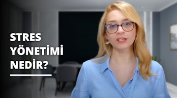 Sarı saçlı, gözlüklü ve mavi gömlekli bir kadın öne doğru bakmaktadır. Yanında siyah zemin üzerine beyaz bir yazı vardır. Siyah beyaz tabelanın üzerinde beyaz harfler yazılıdır. Kadının boynu yakın çekimde görülebilmektedir. Vücudu bulanık bir görüntüde görülüyor ve bacağı da bulanık bir görüntüde görülüyor. Arka planda beyaz bir nesne var ve o da bulanık.