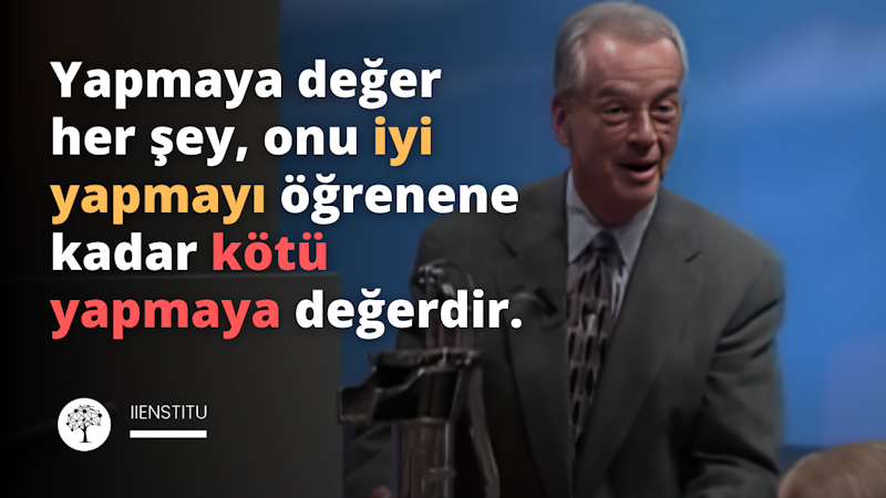 Bu fotoğrafta takım elbiseli bir adam ağzı hafifçe açık bir şekilde karşıya bakmaktadır. Alnı yakın plandadır ve arkasında siyah bir zemin üzerinde sarı bir 'Y' harfi vardır. Sağında siyah bir yüzey üzerinde siyah bir kare, solunda ise mavi bir nesneyi kavrayan bir kişinin eli var. Fotoğrafın alt kısmında ise siyah beyaz bir logo yer alıyor. Takım elbiseli adam iyi aydınlatılmış ve renkler çok keskin ve canlı. Kendinden emin ve profesyonel görünüyor ve giydiği takım elbise yüksek kaliteli bir kumaştan yapılmış.