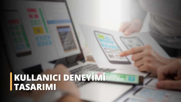 Bu görsel, Kullanıcı Deneyimi Tasarımı (UX Design) ile ilgili çevrimiçi bir kursa katılan bir kişiye aittir. Elinde kurstaki materyallerin yazılı olduğu bir kağıt tutuyor ve parmağıyla işaret ederek materyalin önemini gösteriyor. Kişi odaklanmış ve dikkatli görünerek eğitimin önemini vurguluyor. Görselde ayrıca arka planda bir bilgisayar görülmekte ve bu da çevrimiçi kursun amacını vurgulamaktadır. Genel olarak bu görsel, UX Tasarımının uygun eğitim ve odaklanma yoluyla öğrenilebilecek ve geliştirilebilecek bir beceri olduğu fikrini aktarıyor. Alanda rekabetçi kalabilmek için en son teknolojiler ve trendlerle güncel kalmanın önemini vurguluyor.