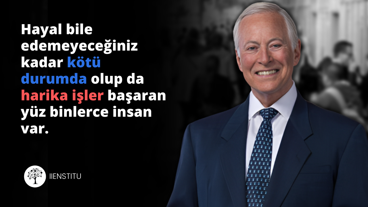 Şık bir takım elbise giymiş ve kravat takmış bir adam yakın çekimde gülümserken görülüyor. Yüzü biraz bulanıktır ama yine de tanınabilir durumdadır. Takım elbisesi açık gri, kravatı ise koyu bordo renktedir. Kravatı standart bir düğümle bağlanmış ve takım elbisesinin içine sokulmuştur. Yüzünde hafif bir gülümsemeyle doğrudan kameraya bakarken görülüyor. Kısa, koyu renk saçları ve sinekkaydı traşlı bir yüzü vardır. Gözleri sanki anın tadını çıkarıyormuş gibi hafifçe kısıktır. Profesyonel bir ortamda olduğu anlaşılıyor ve kendinden emin ve rahat görünüyor.