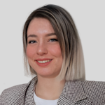 Yüzünde parlak bir gülümseme olan genç bir kadın doğrudan kameraya bakıyor. Uzun siyah saçları, koyu kahverengi gözleri ve açık bir teni var. Mavi-gri bir kazak, beyaz kot pantolon ve siyah botlar giyiyor. Dudakları hafifçe ayrılmış ve gözleri neşe ve mutluluk dolu. Başı hafifçe yana eğik, bu da gülümsemesinin daha da sıcak görünmesini sağlıyor. Bu anda kendinden emin ve memnun görünüyor, parlak gözleri ve gülümsemesi neşe saçıyor.