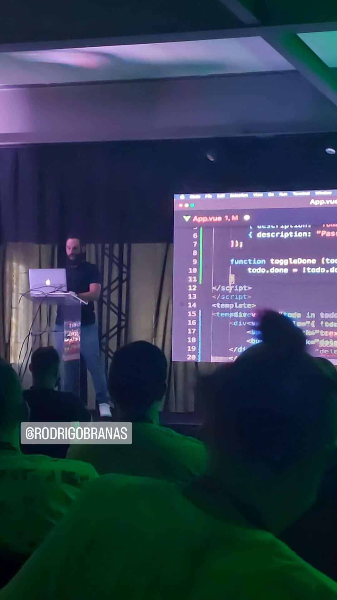 rodrigo branas no palco com o vs code aberto ao fundo no telão