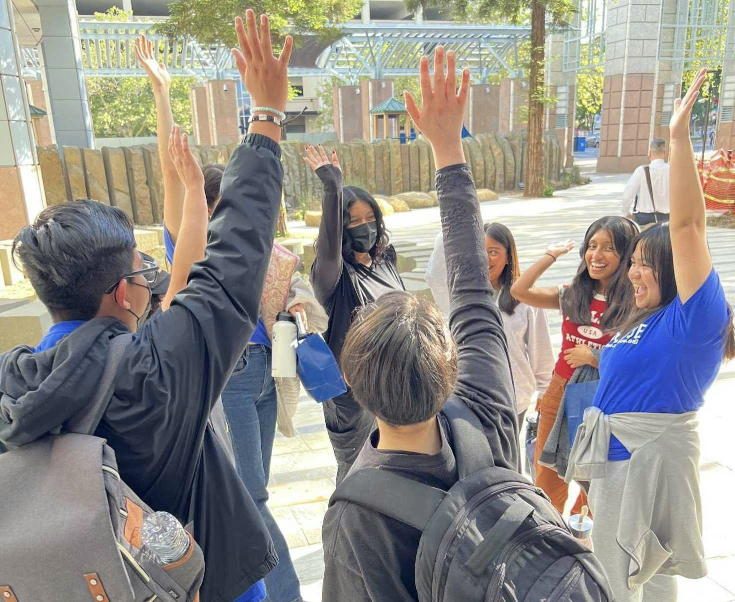 CAUSE, CPI, WWRC, and LAANE staff raising their hands in a circle and celebrating the passage of the ACF