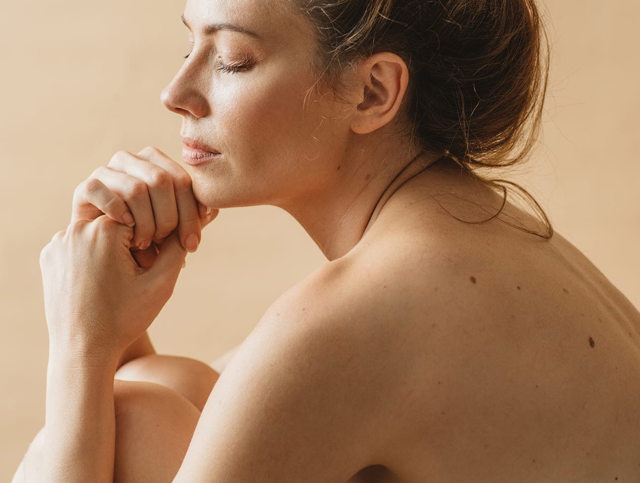 woman hugging knees with bare back