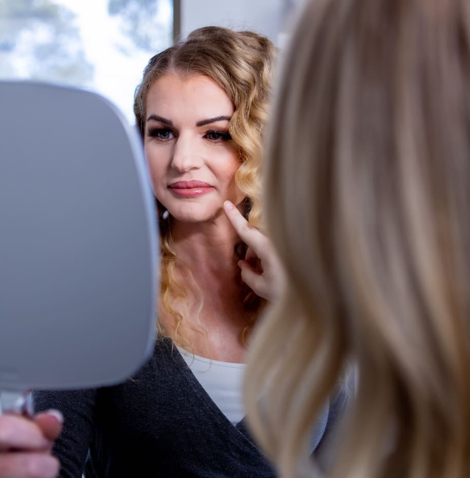woman looking in a hand held mirror