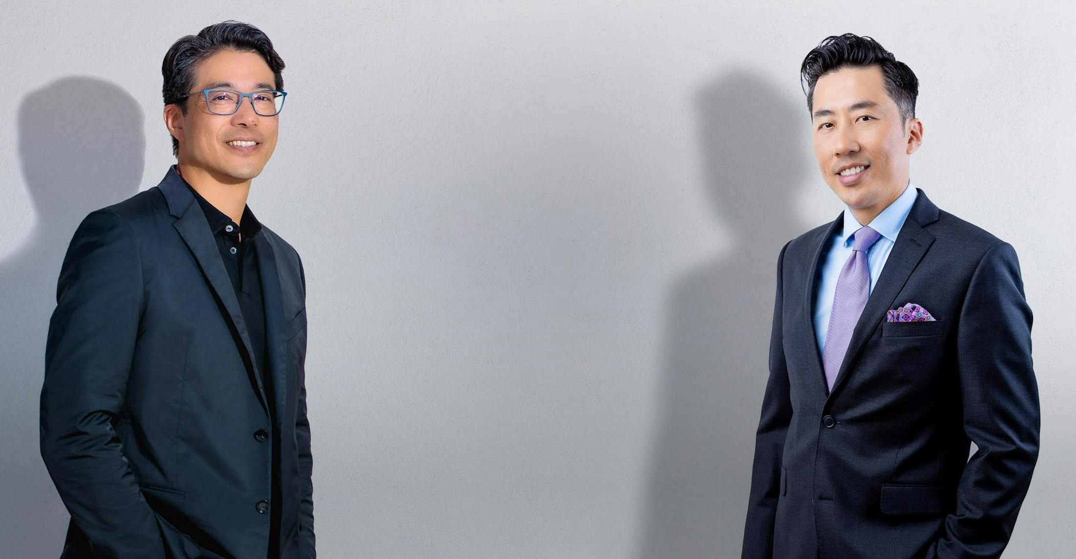 Dr. Liu and Liu, both wearing suits, stand in front of a backdrop.