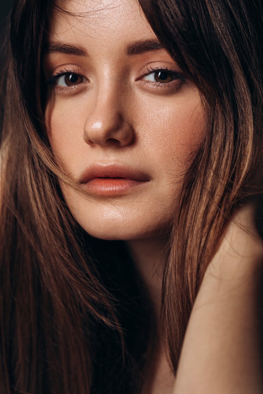 Close up of young woman with beautiful glowing skin with long hair in studio shoot