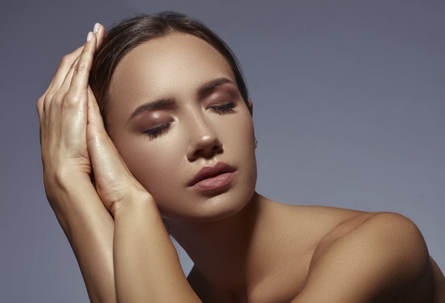 Young woman resting head on hands with eyes closed with full makeup in studio shoot