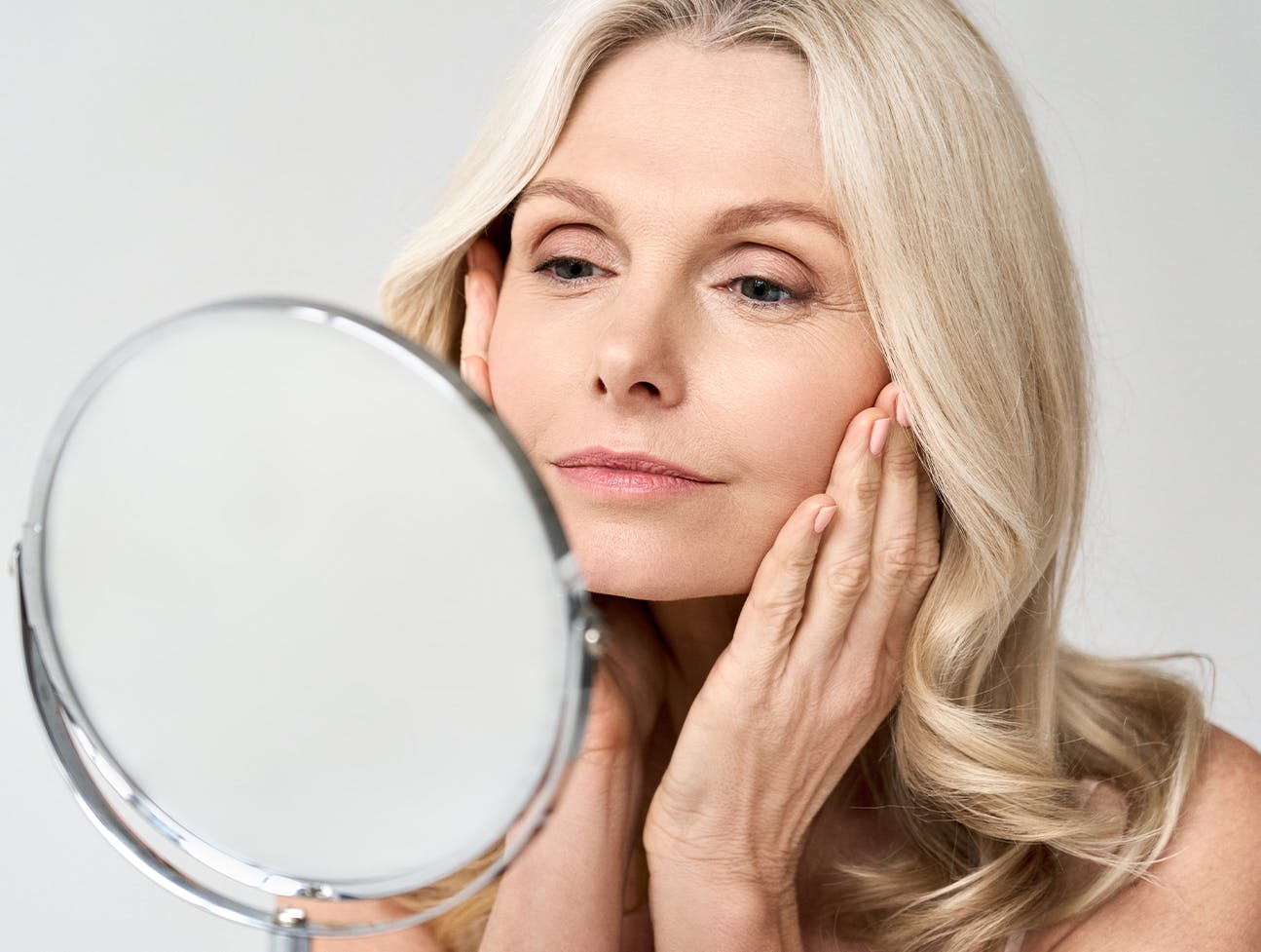 Middle aged woman examining her face in a mirror.