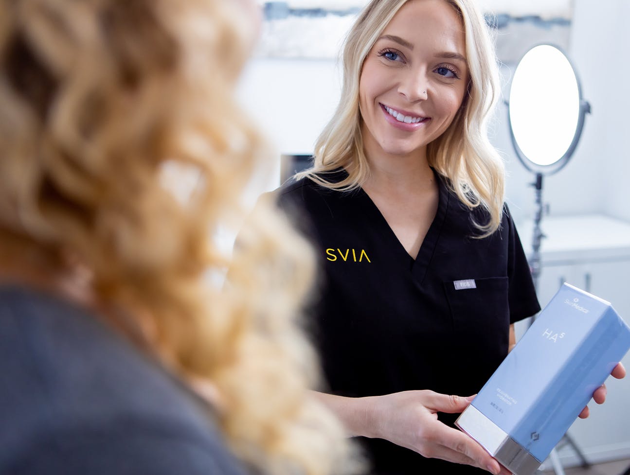 staff showing patient skin care product