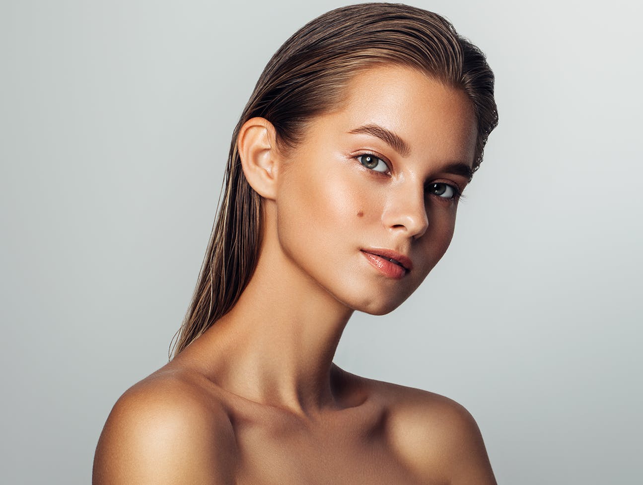 woman with brown hair brushed back and a beauty mark