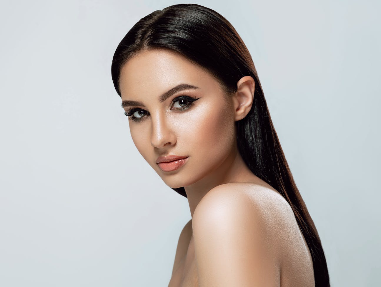woman with straight black hair looking over shoulder