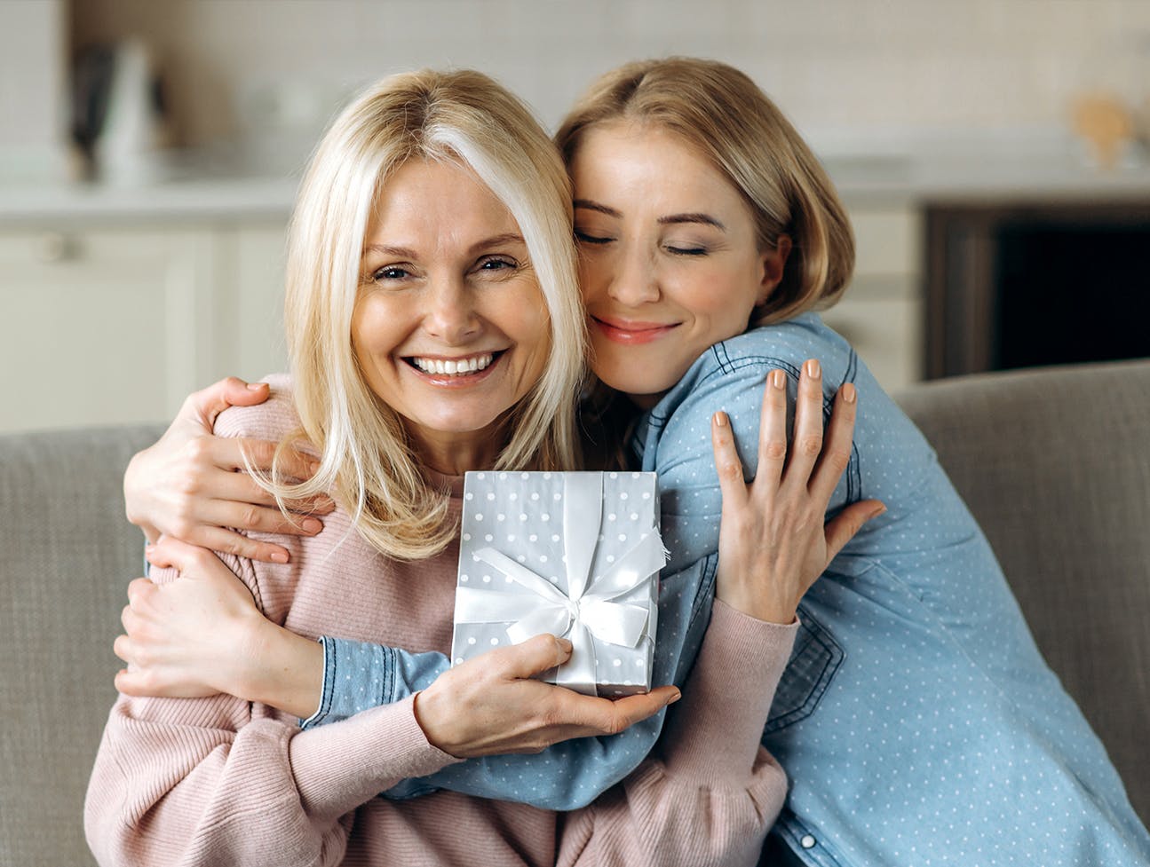 two women hugging hoding a wrapped gift