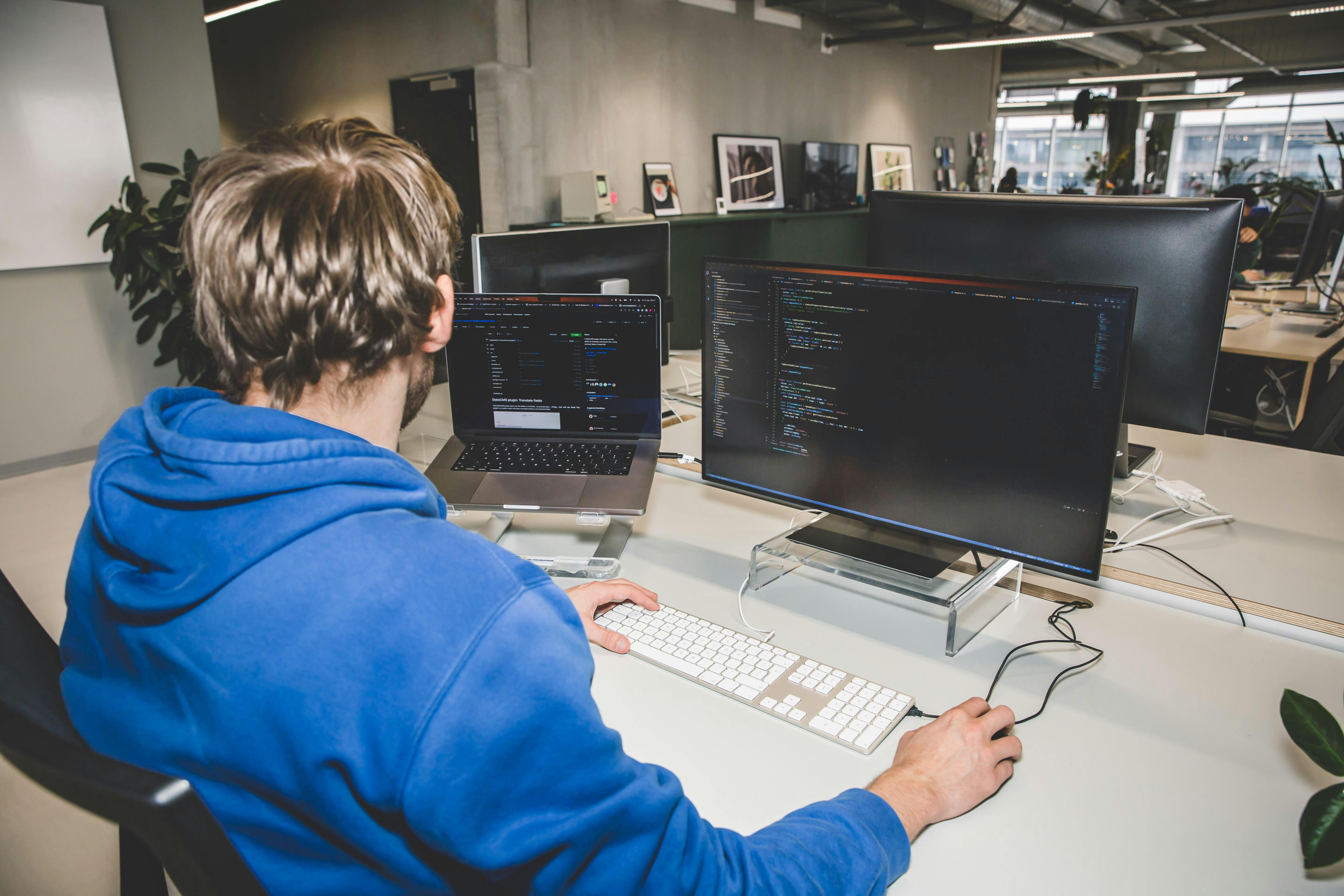 Developer werk aan een bureau met twee schermen