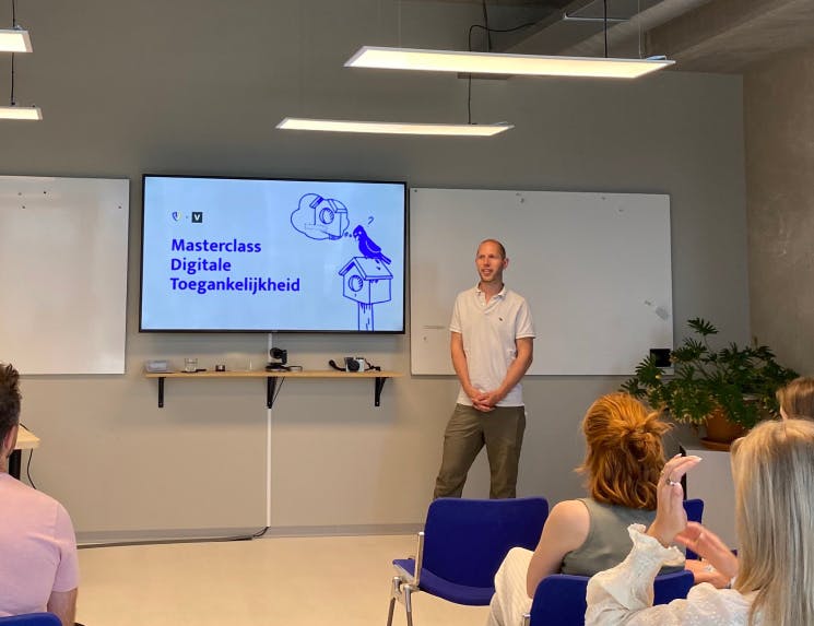 A men presenting next to a screen that says 'masterclass digitale toegankelijkheid'