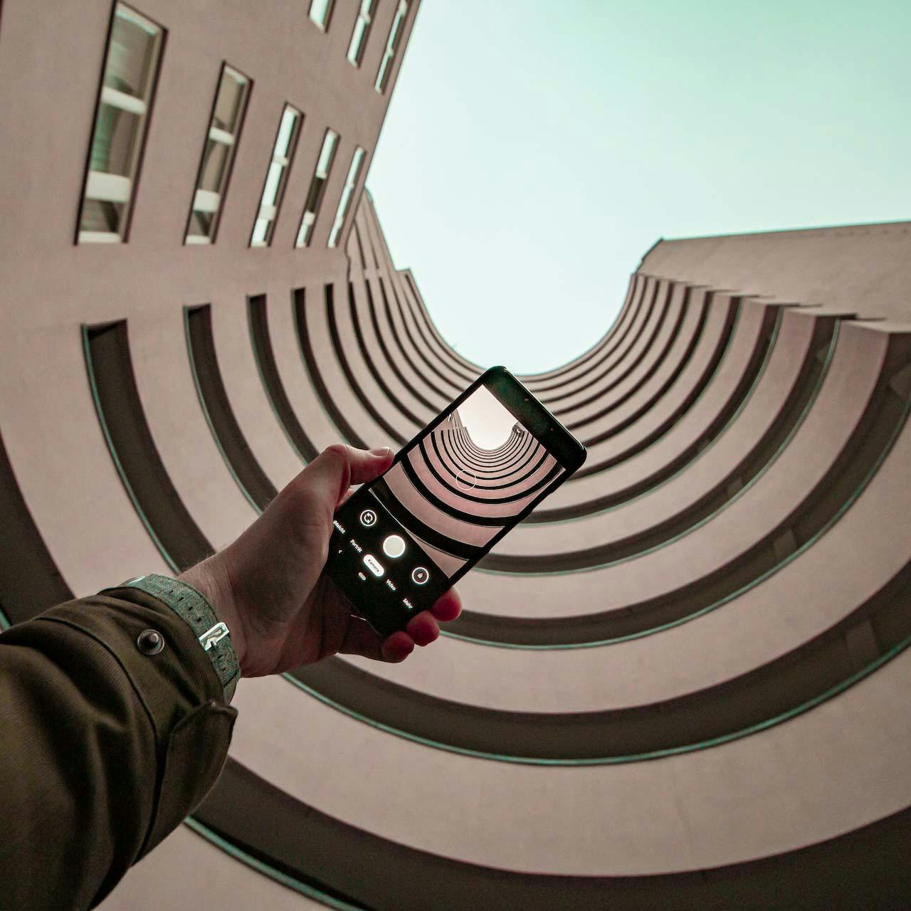 Foto di una persona che scatta con uno smartphone una foto di un palazzo dal basso verso l'alto