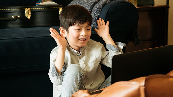 A young boy joyfully watches his laptop screen
