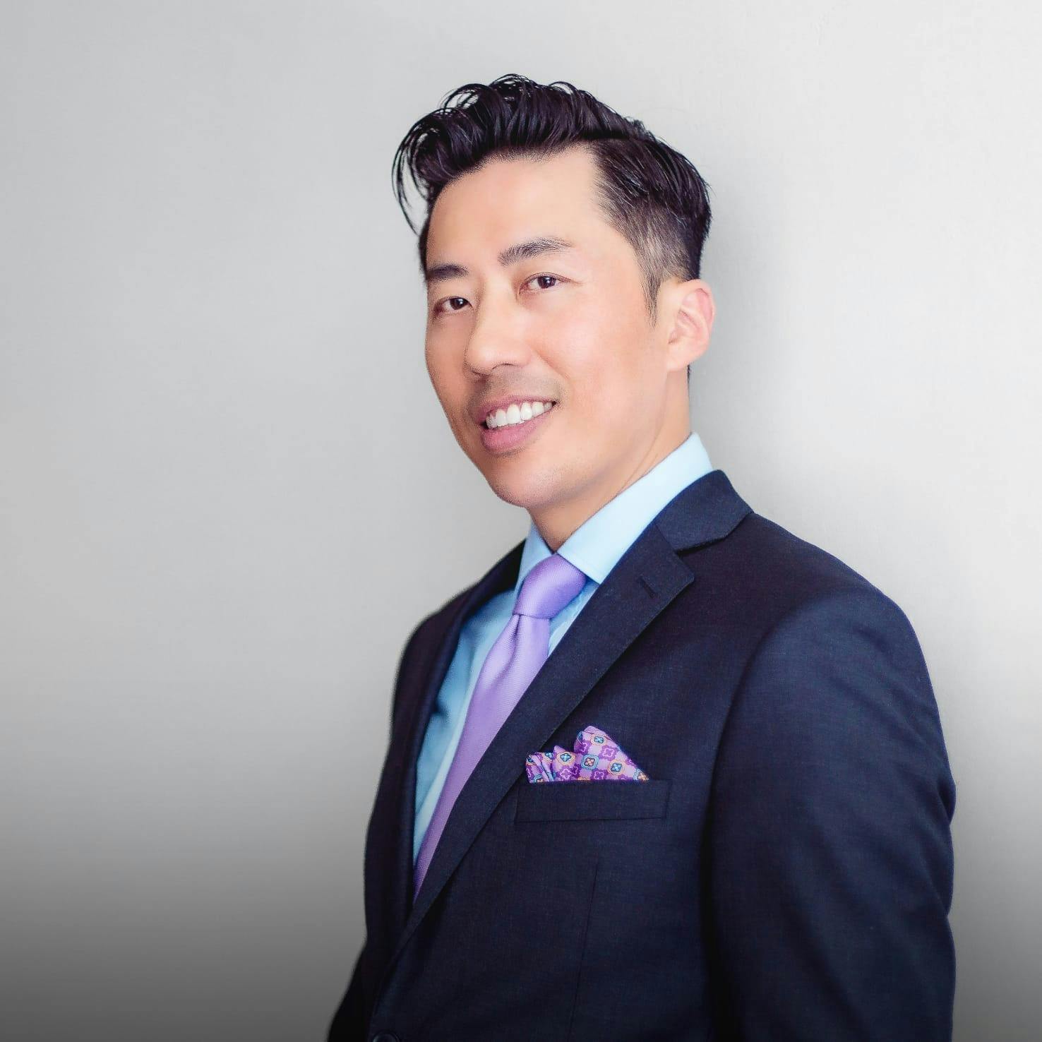 Dr. Tom Liu in a suit, smiling.