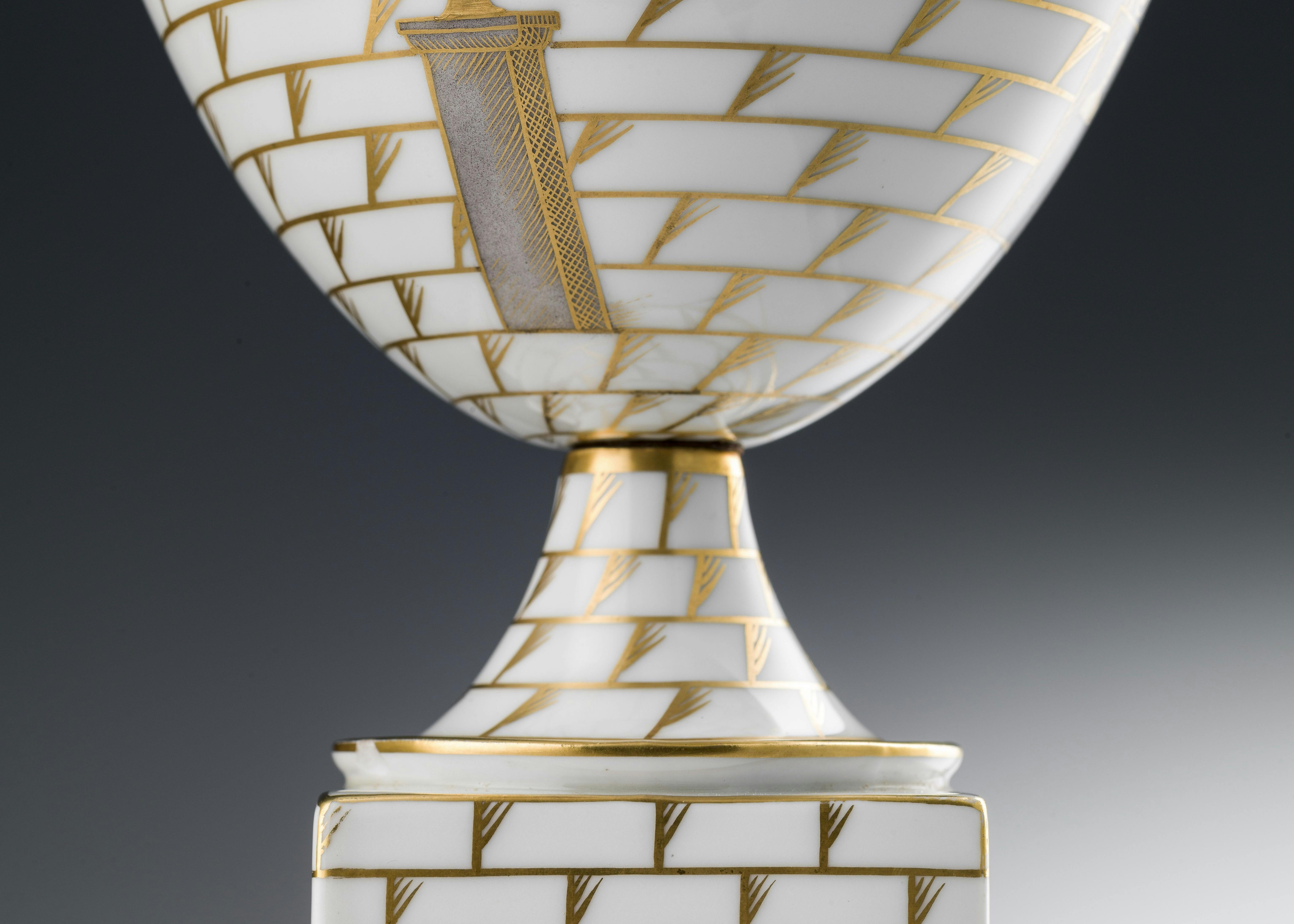 Dettaglio della base del vaso bianco con decori policromi e oro su fondo bianco