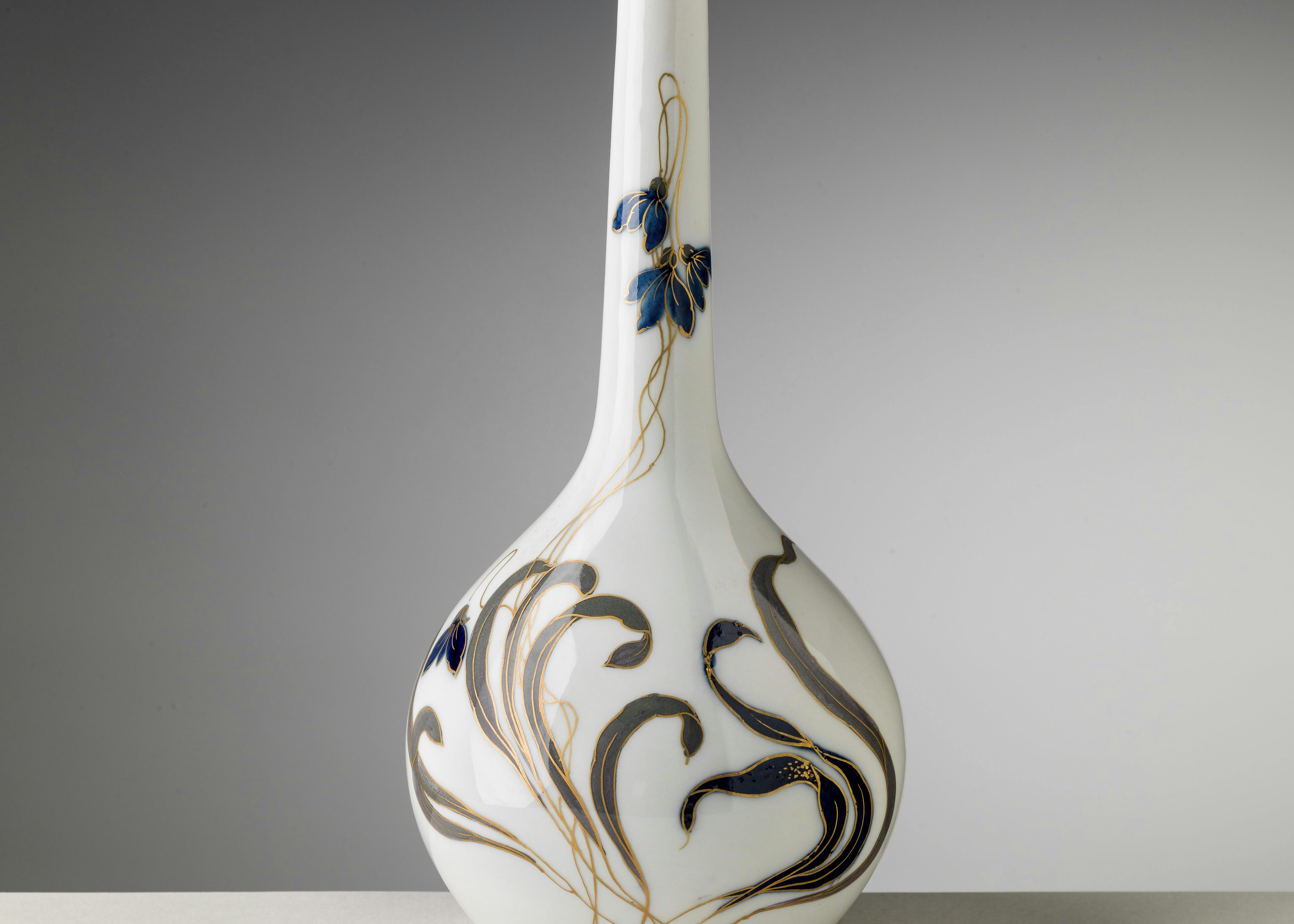 Il vaso a fondo bianco è decorato con foglie e fiori di ciclamini viopla e oro