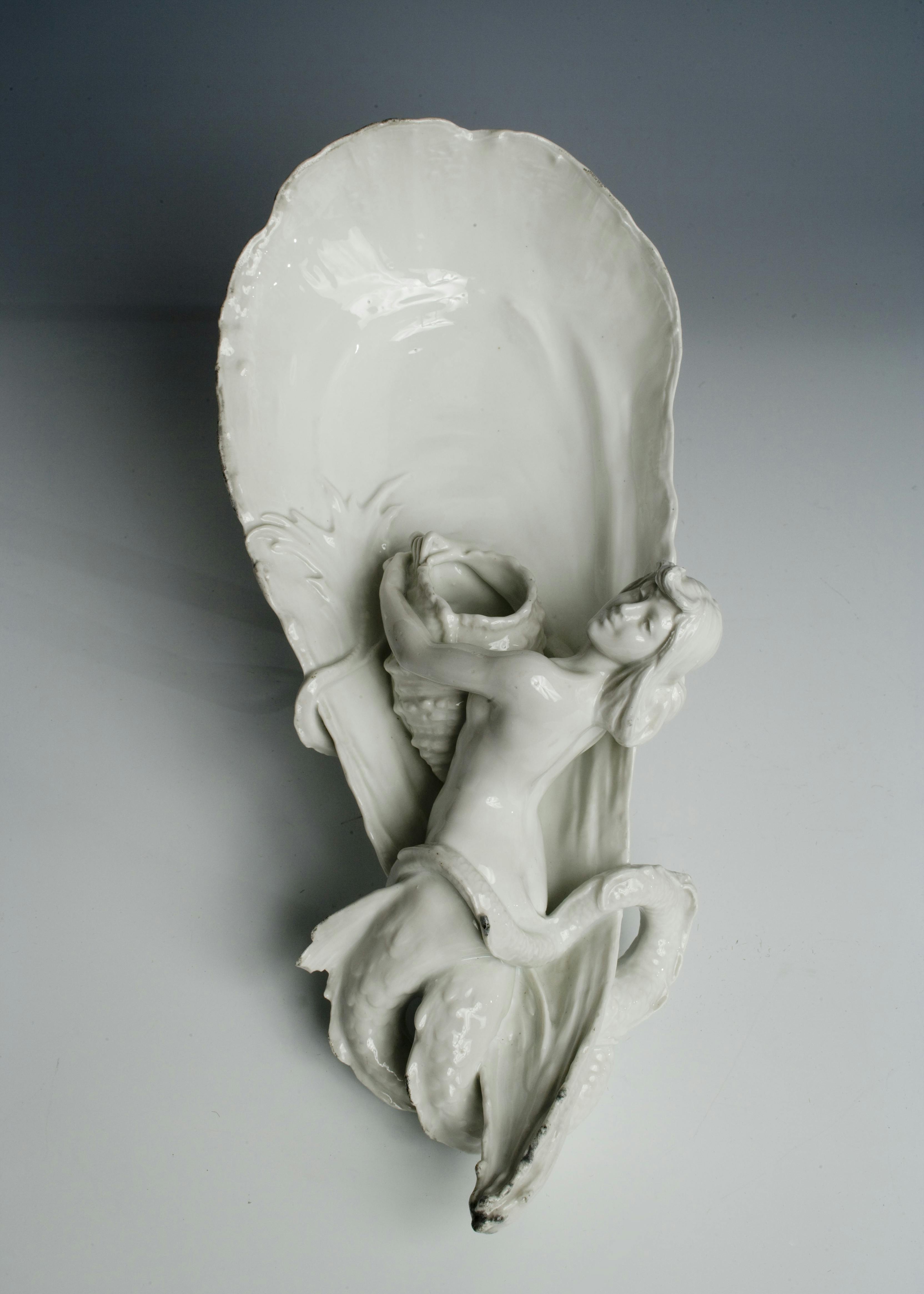 Manufatto in porcellana bianca a forma di ostrica con sirena in rilievo