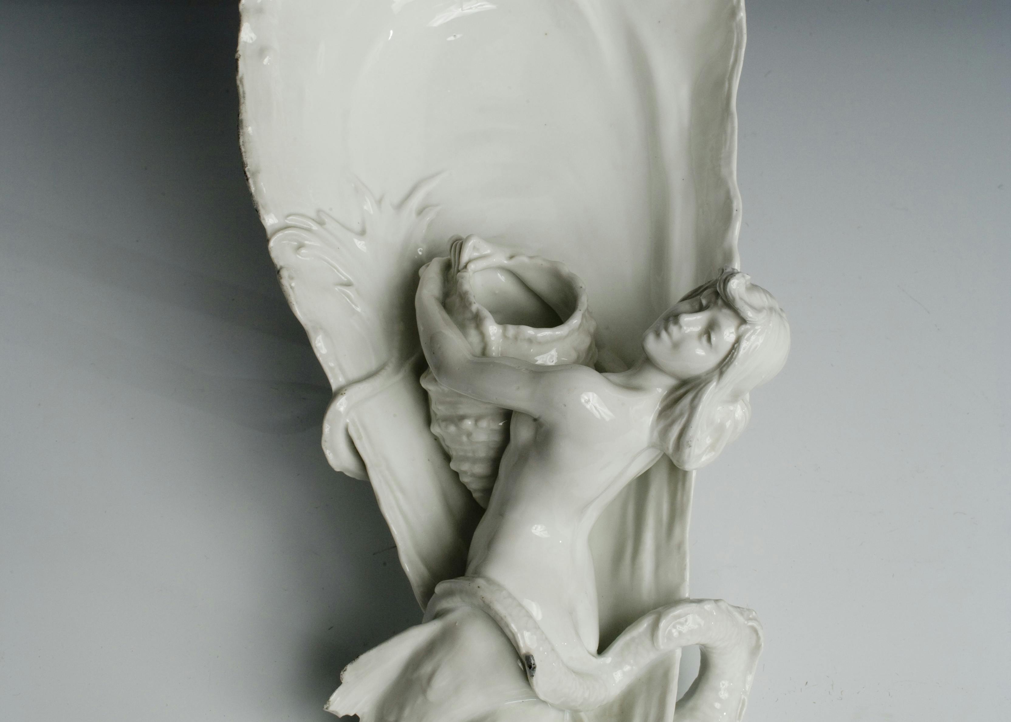 Manufatto in porcellana bianca a forma di ostrica con sirena in rilievo