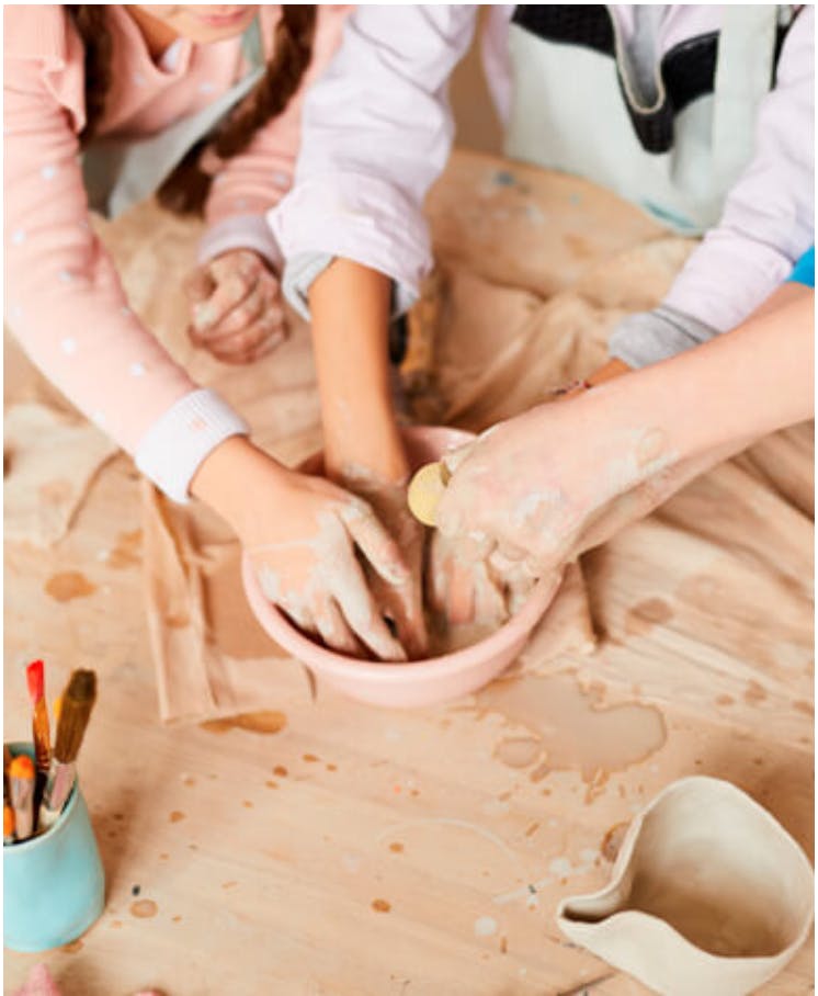 Persone intente a lavorare la ceramica su un tavolo con diversi recipienti