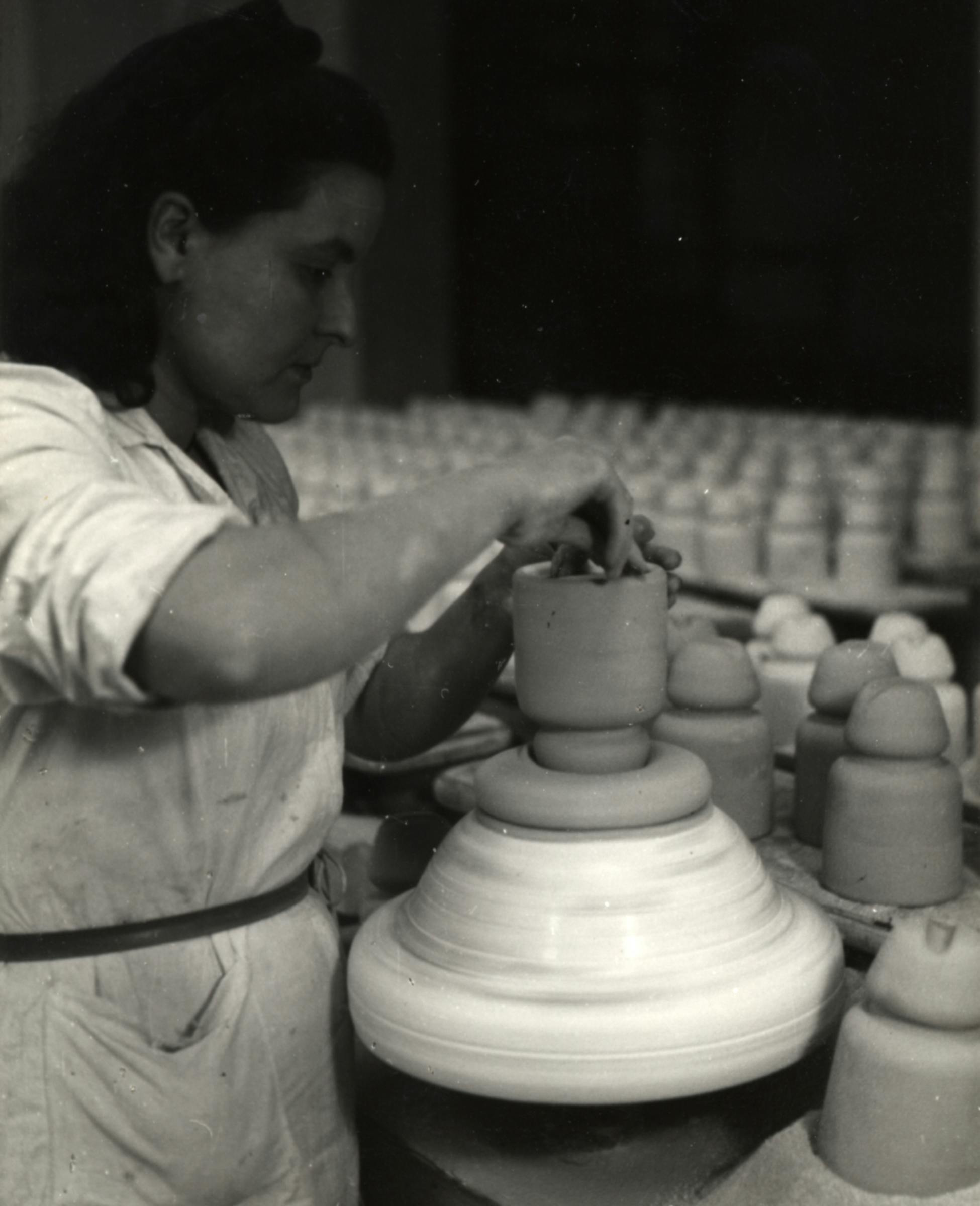 Un'operaia intenta a lavorare su un manufatto ceramico
