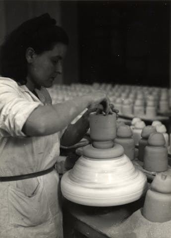 Un'operaia intenta a lavorare su un manufatto ceramico