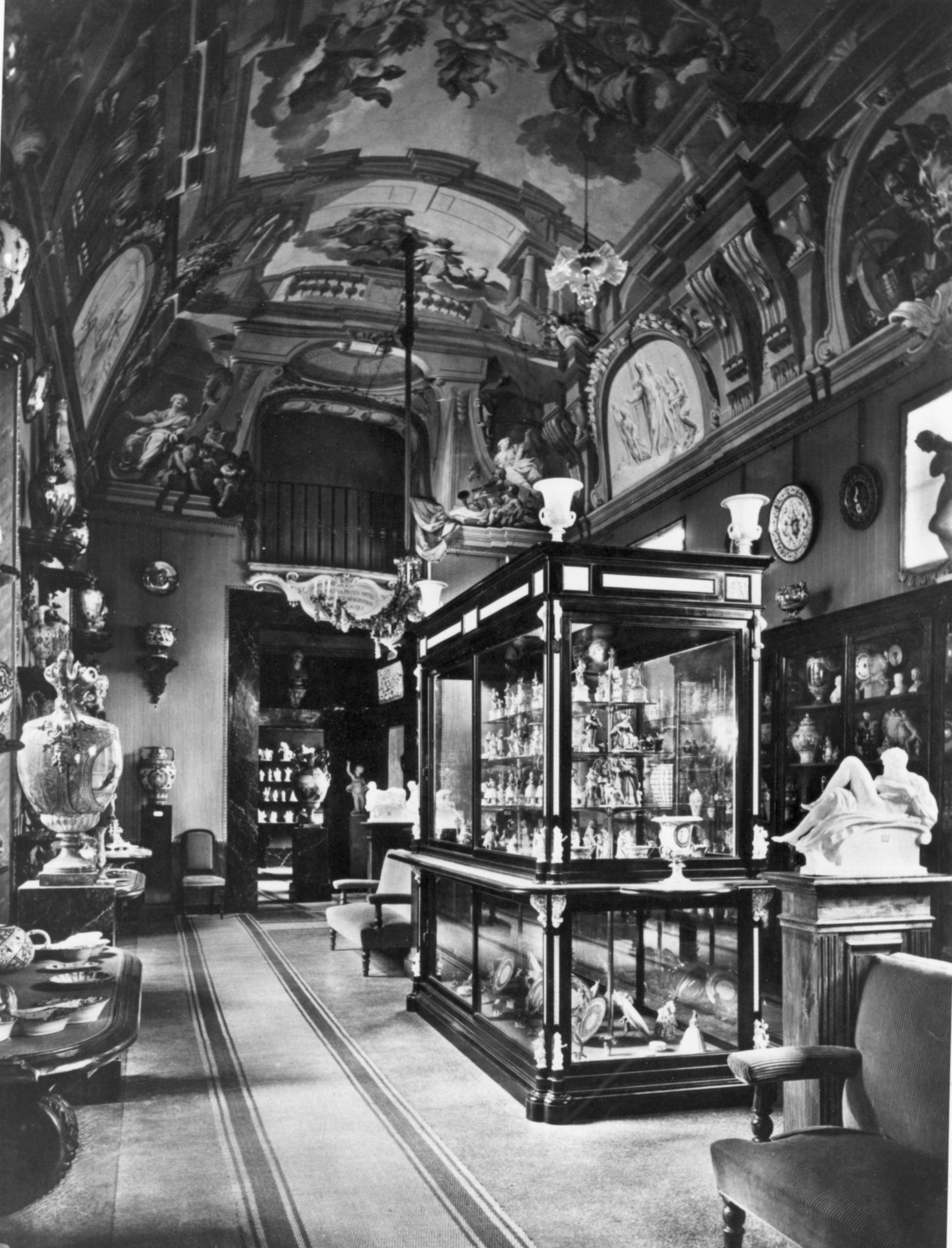 Foto in bianco e nero di una sala affrescata al cui interno sono esposti manufatti in porcellana