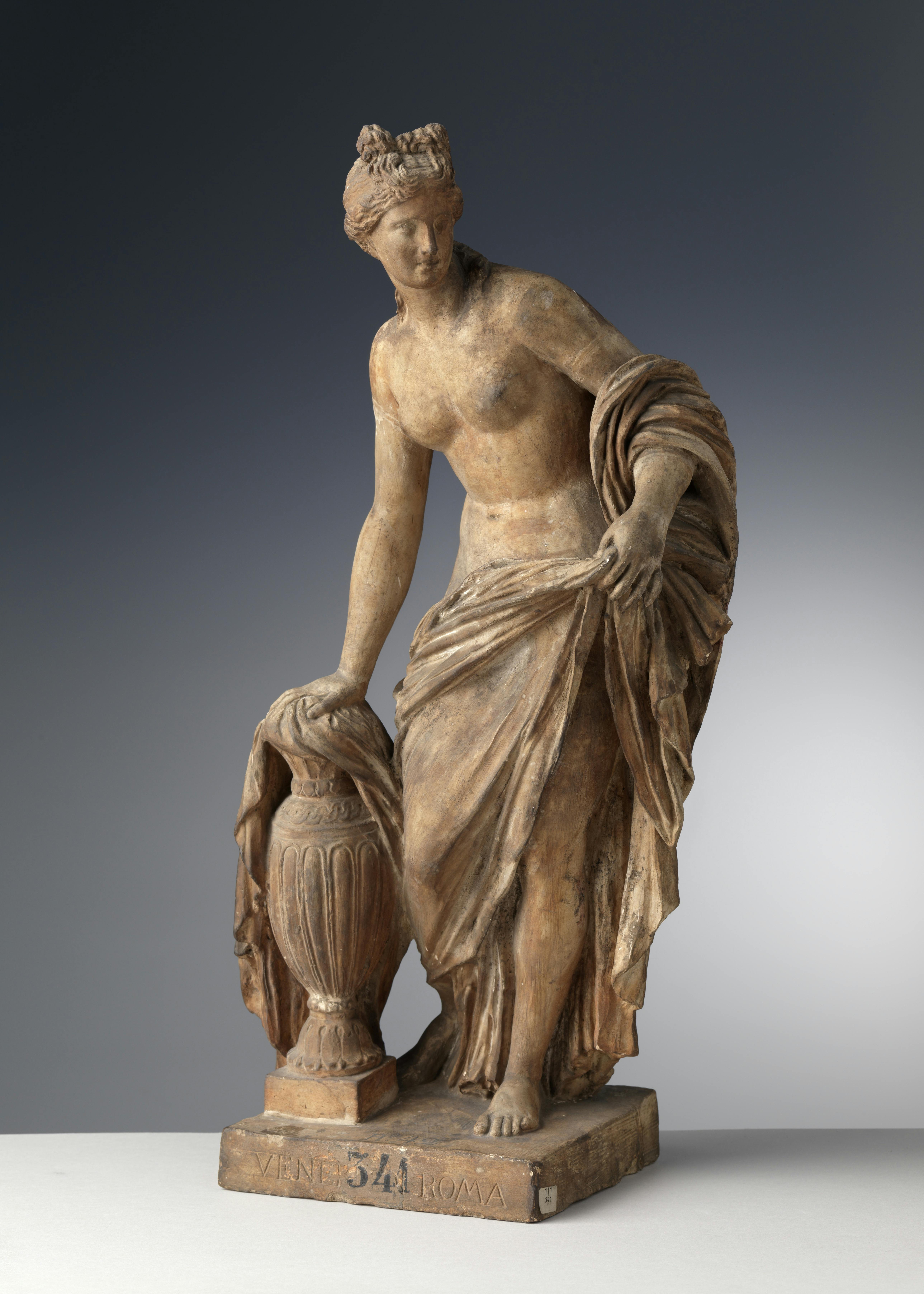 La scultura raffigua una donna coperta da un ampio panno che appoggia la mano su un'anfora