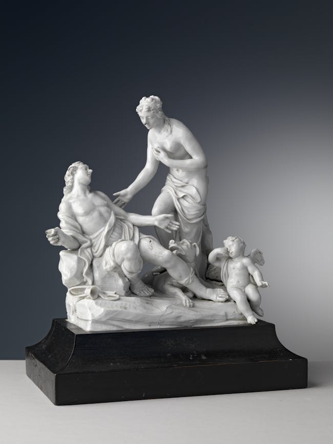 Gruppo scultoreo in porcellana bianca con una figura maschile adagaiata, una figura femminile in piedi e un piccolo putto alato