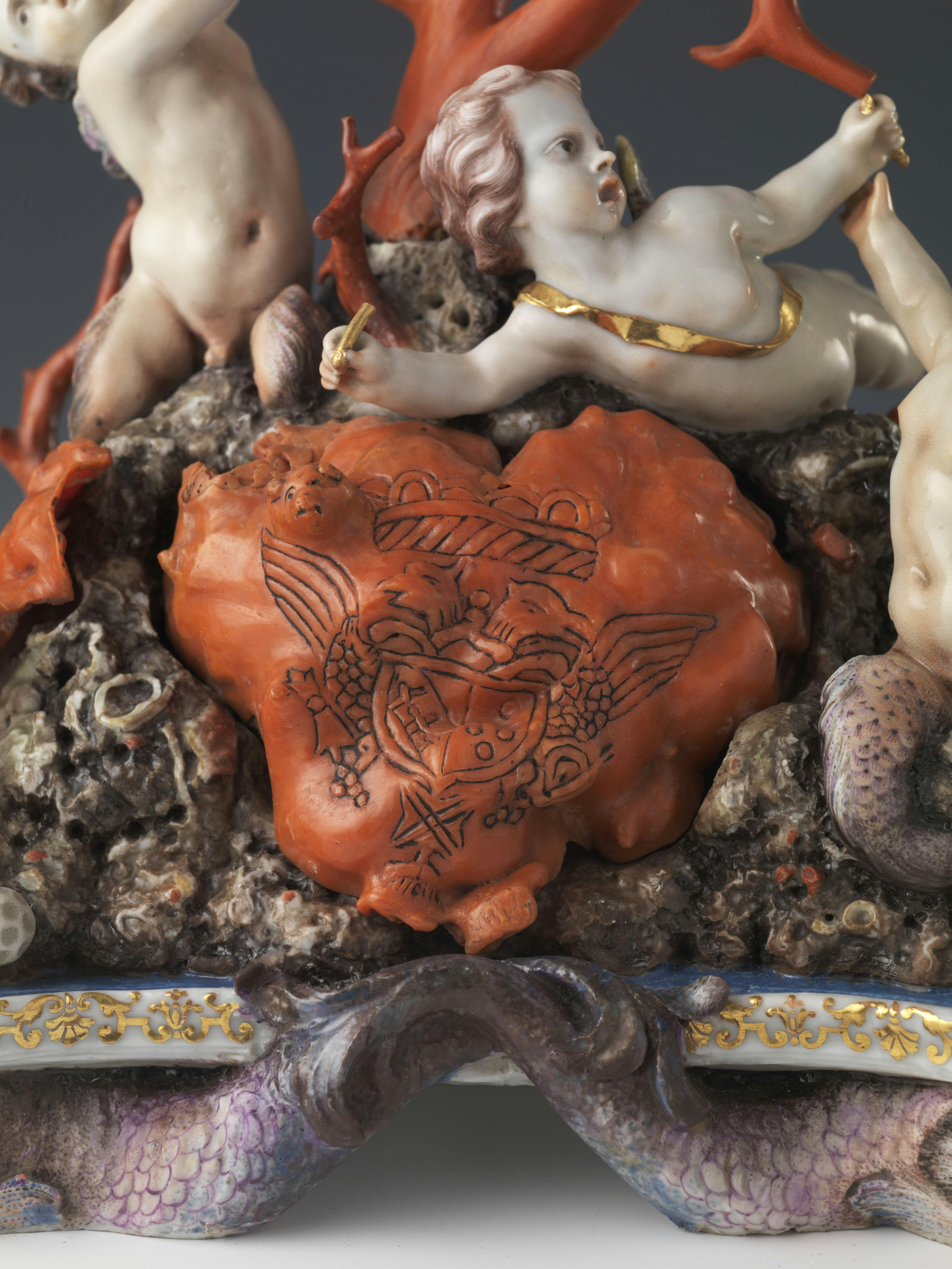 Putto in ceramica appoggiato a un blocco di corallo