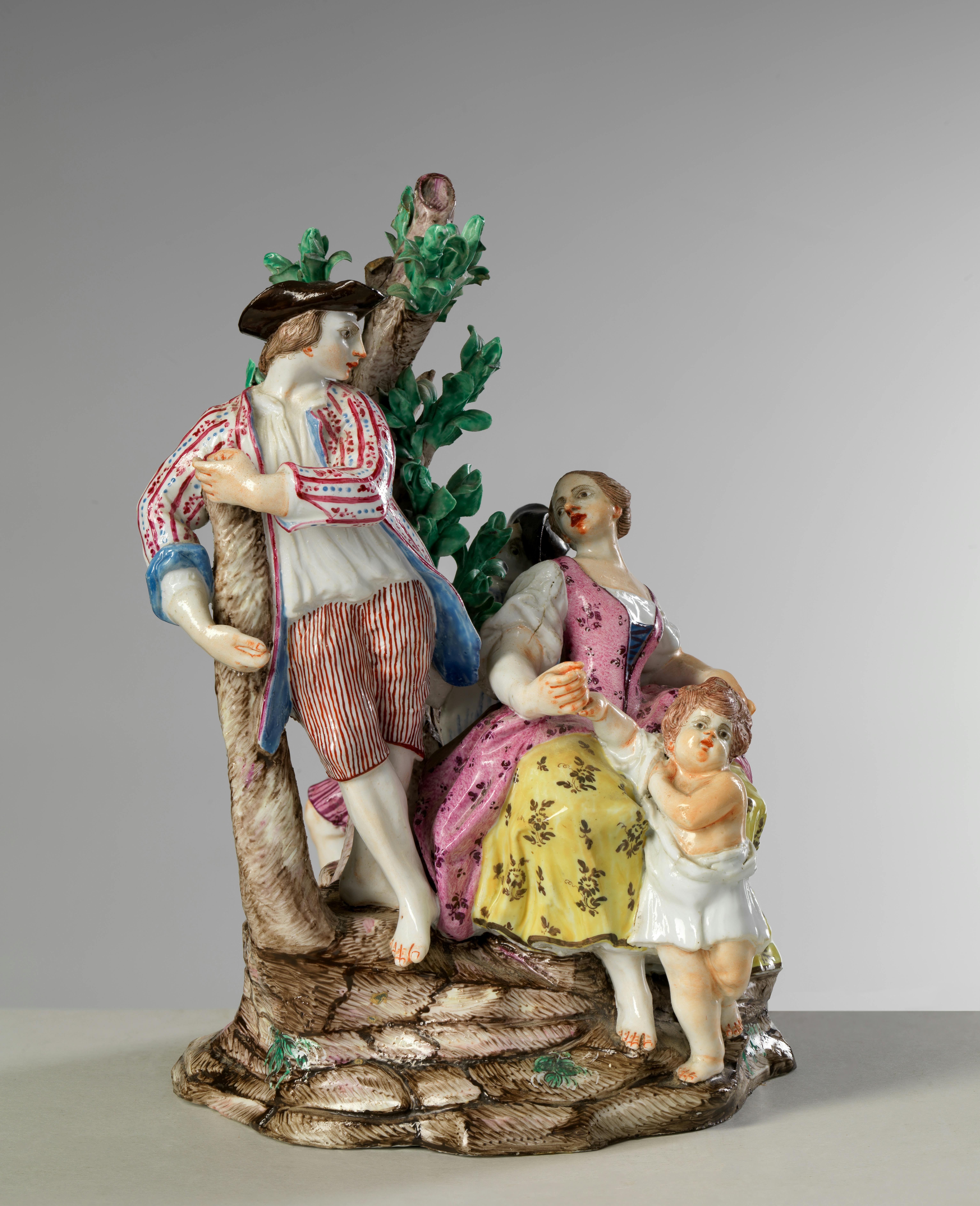 Porcellana colorata con uomo appoggiato a un albero, donna e bambino