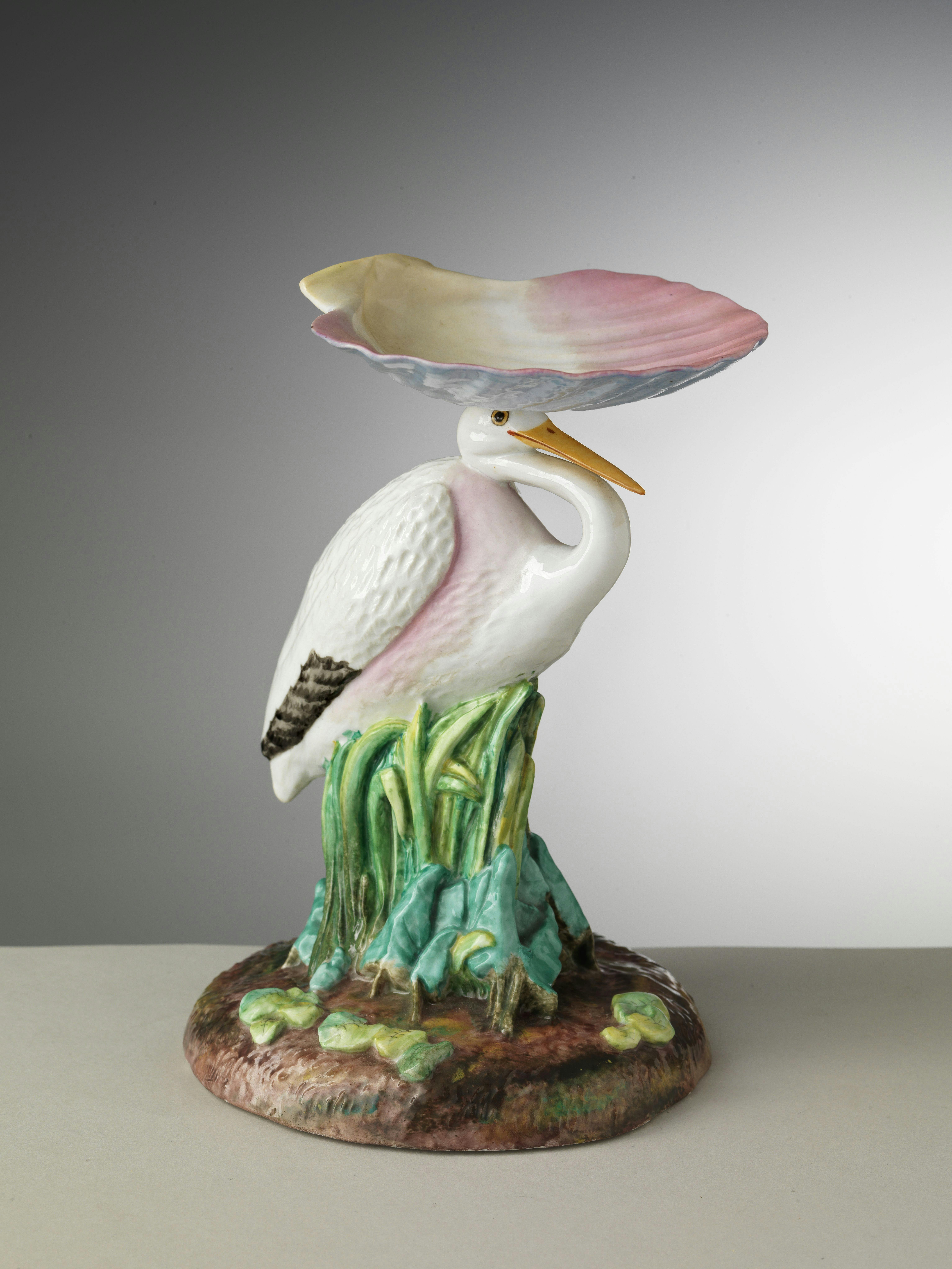 Scultura di porcellana policroma con airone che sostiene sulla testa una conchiglia