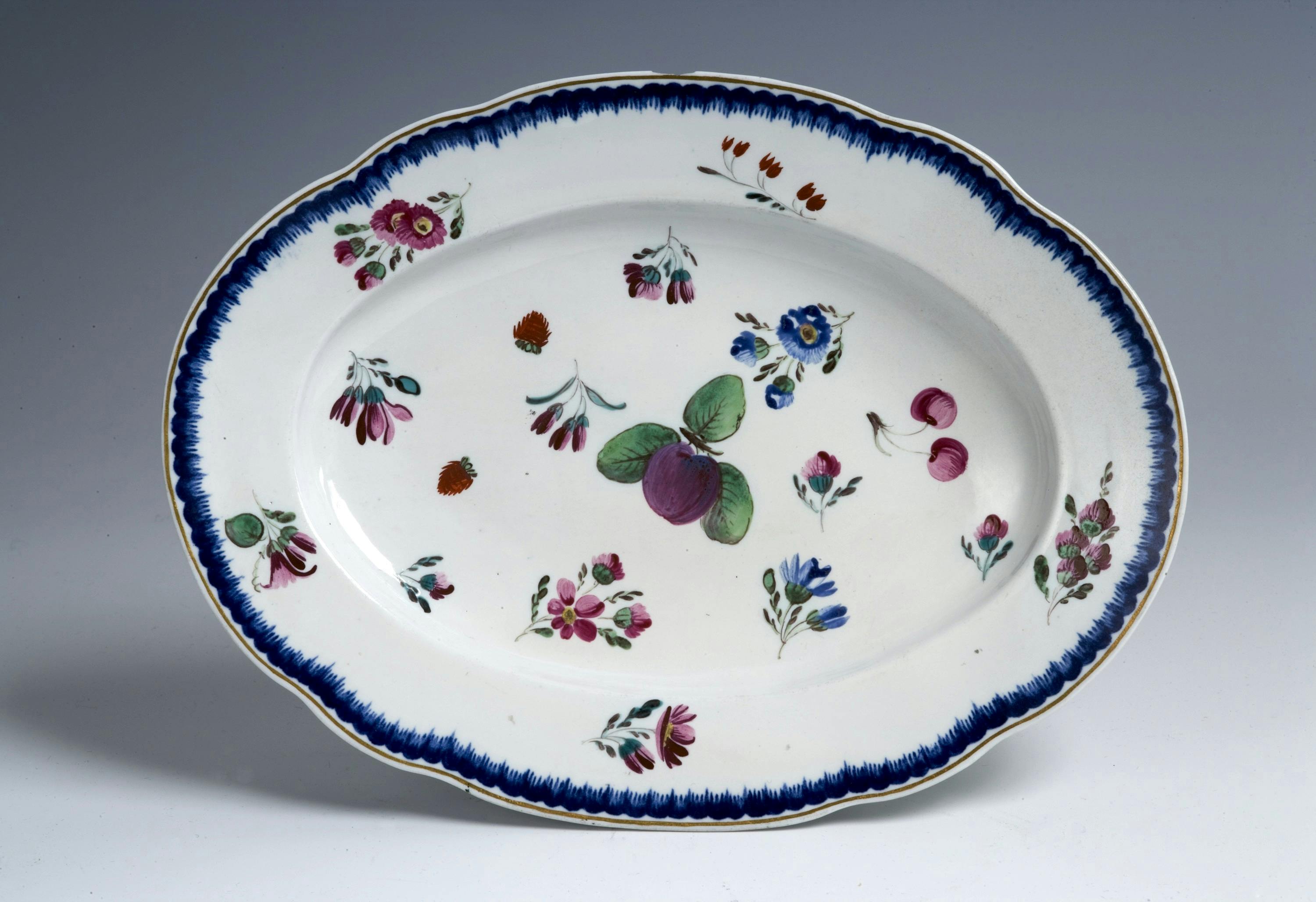 Piatto ovale con bordo blu e decori variopinti a fiori e frutti sparsi