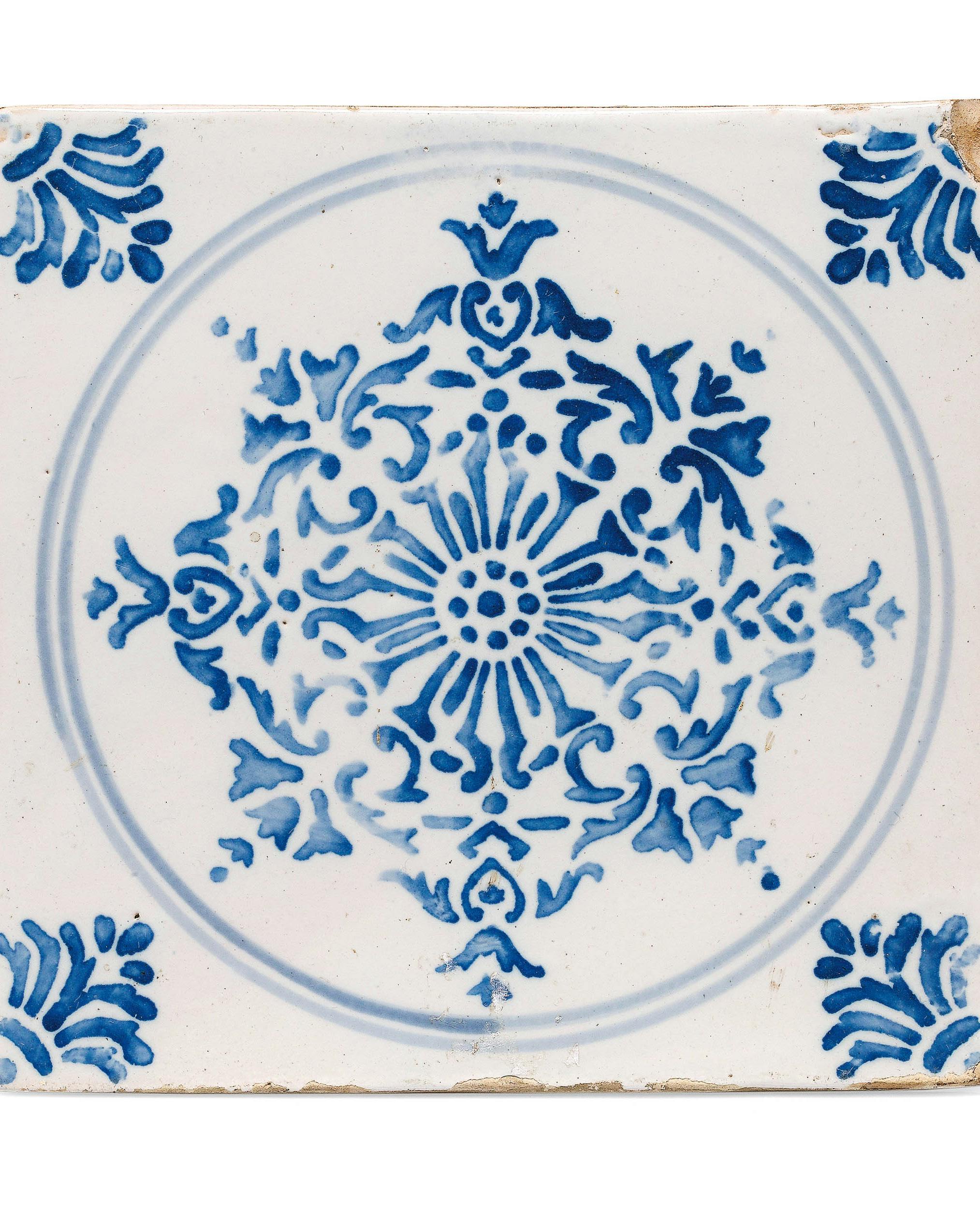 Mattonella quadrata bianca con decoro azzurro con motivi vegetali dentro un cerchio